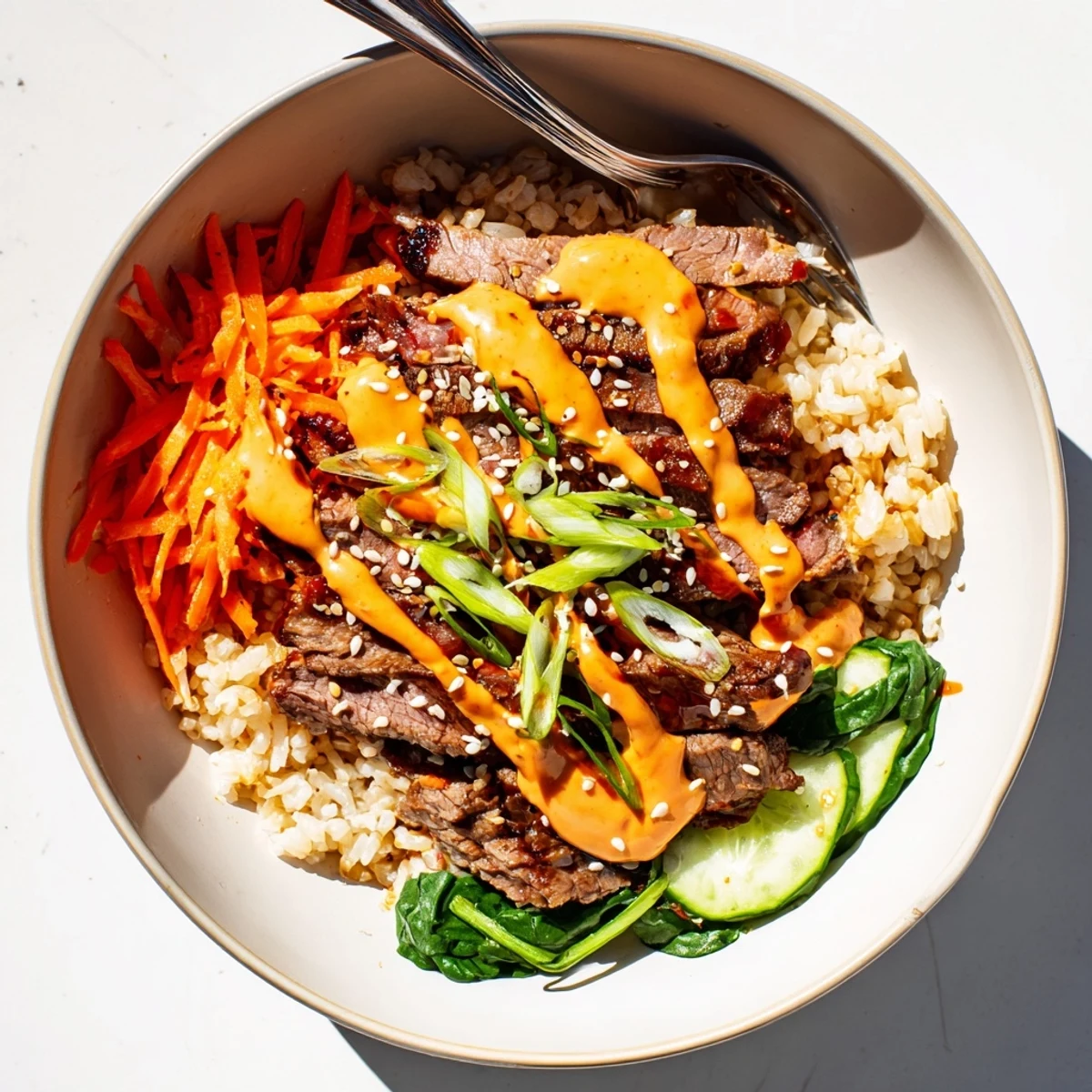 A generous portion of Korean BBQ Steak Rice Bowls featuring tender seared steak, warm rice, and a bold spicy cream sauce.