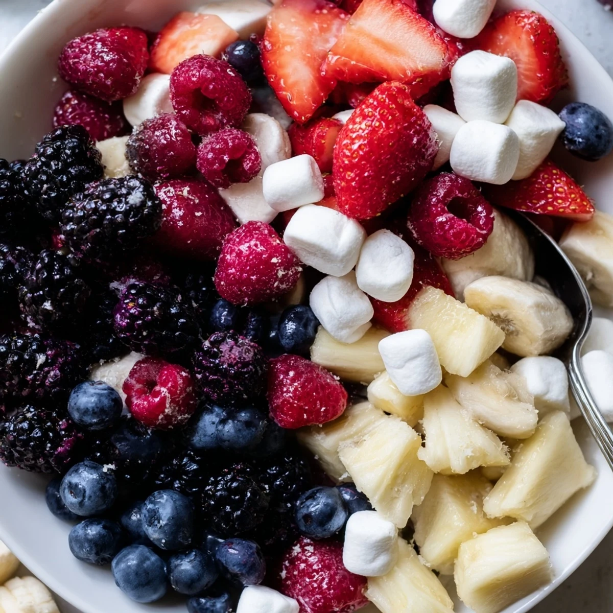 Red White And Blue Fruit Salad piled in bowl, juicy berries and pineapple.