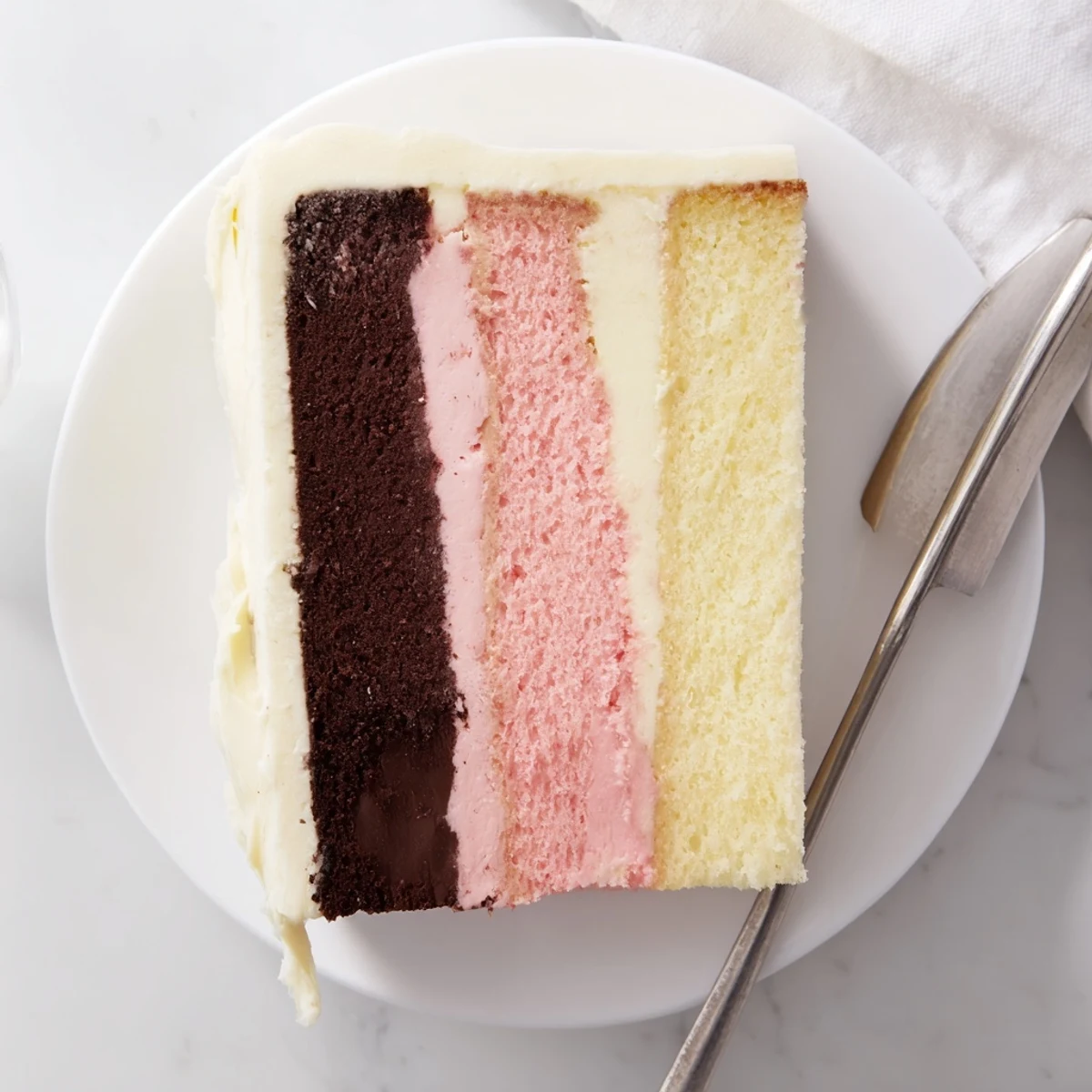 Homemade Neapolitan cake stacked with vibrant horizontal stripes representing classic ice cream flavors, finished with smooth vanilla buttercream and decorative sprinkles