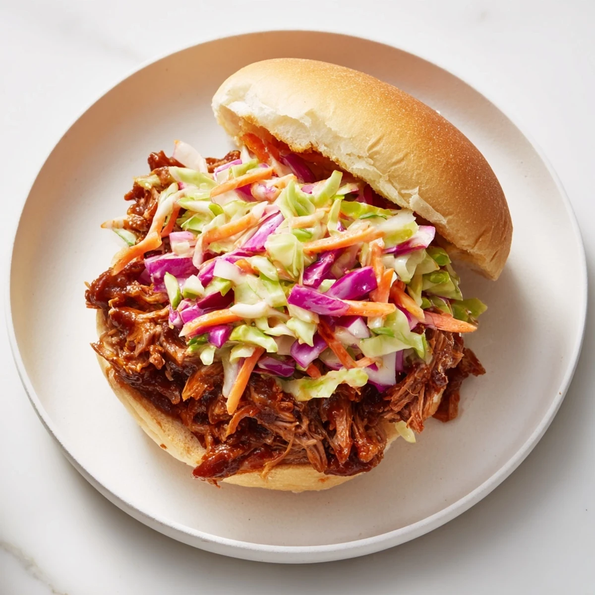 Tender shredded beef in rich smoky BBQ sauce topped with crisp colorful coleslaw on soft sandwich rolls