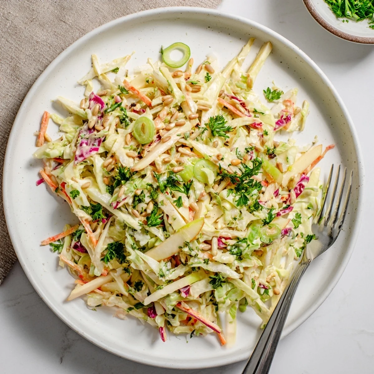Fresh apple coleslaw with shredded cabbage and creamy dressing in a white bowl