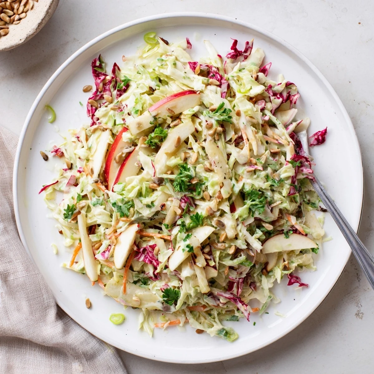 Vibrant apple coleslaw with julienned apples and toasted seeds served at summer picnic