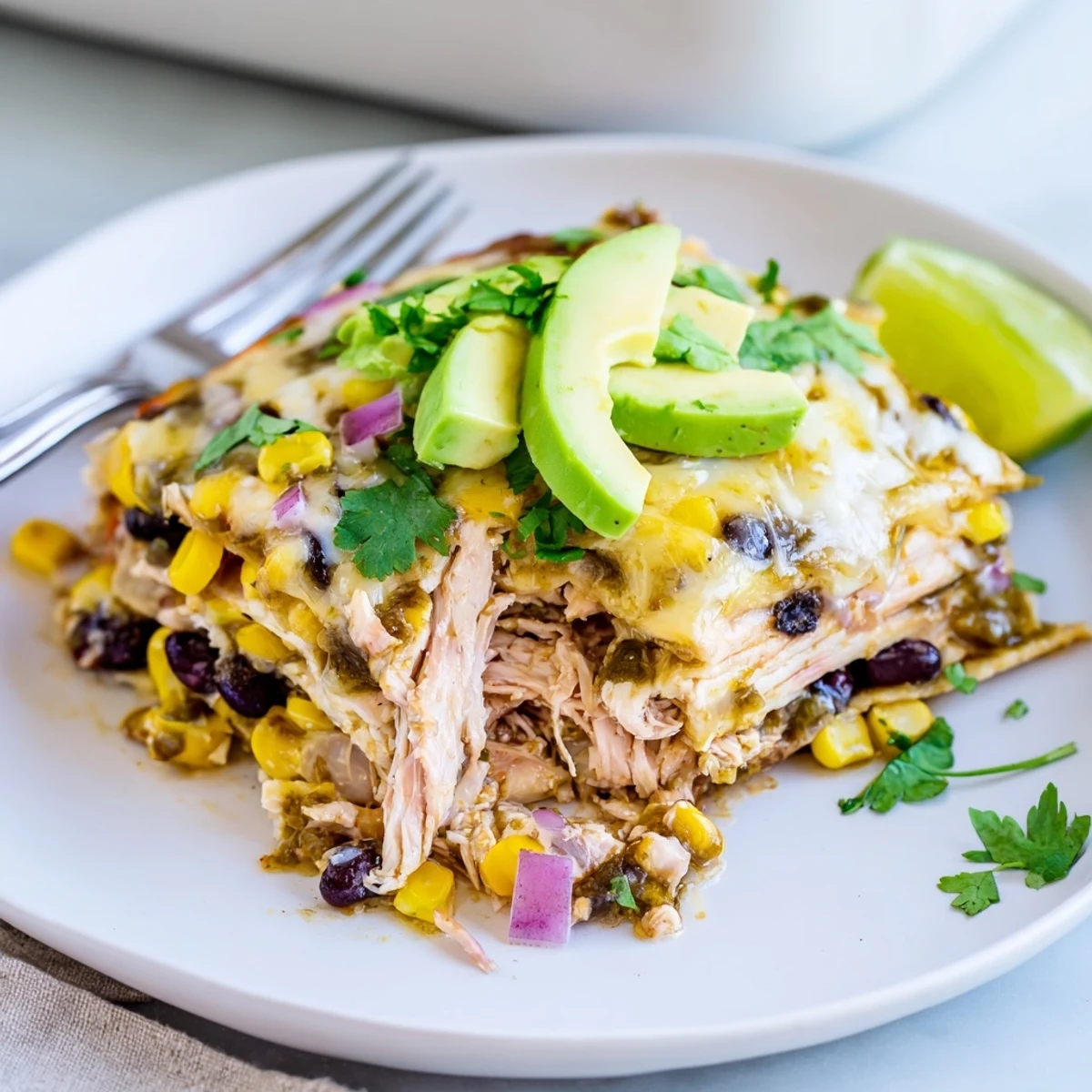 Warm Salsa Verde Chicken Casserole layered with corn tortillas, creamy sauce, lime wedges  