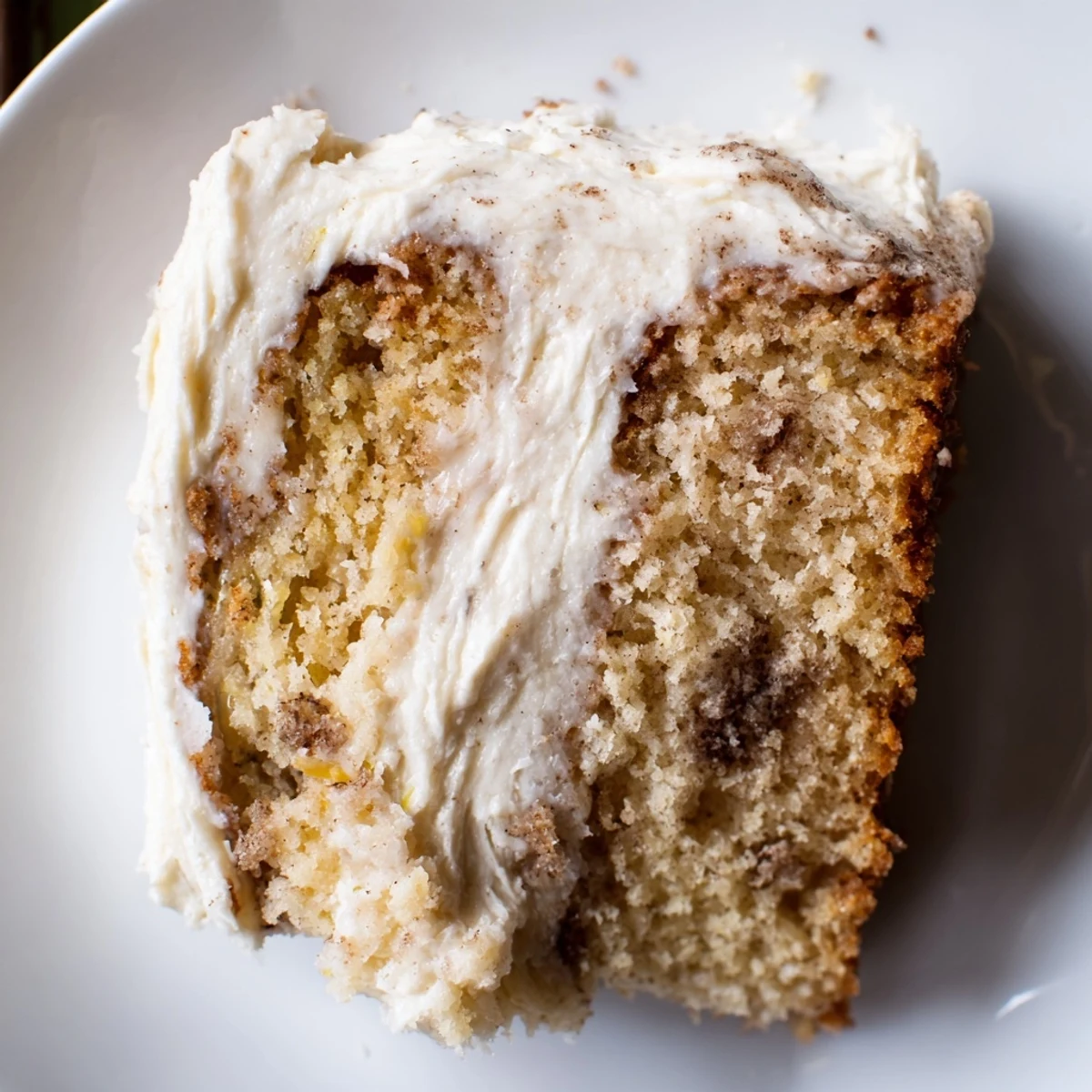 Brown Butter Banana Cake sliced thick with pillowy cream cheese frosting on a rustic wooden board