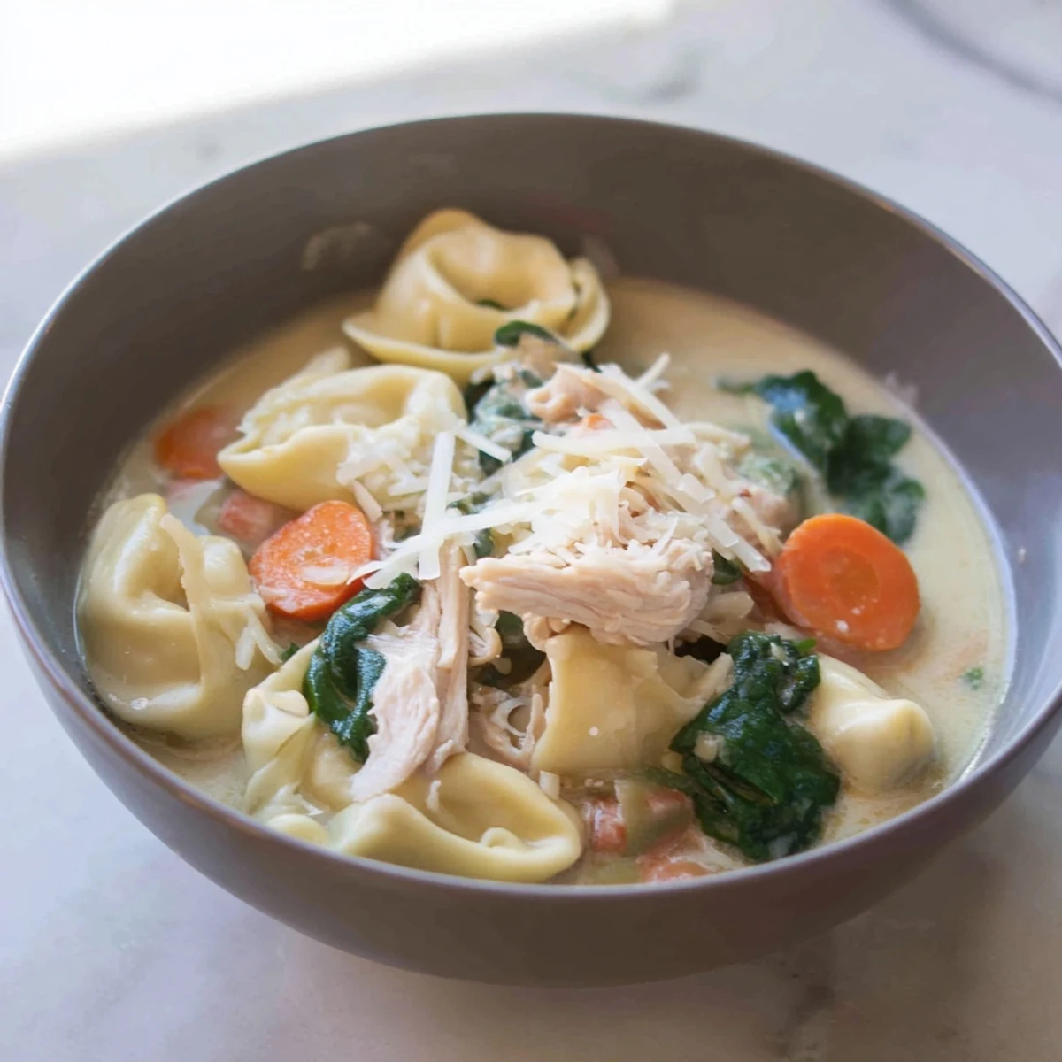 Rich and hearty Crockpot Chicken Tortellini served in a creamy broth with cheese