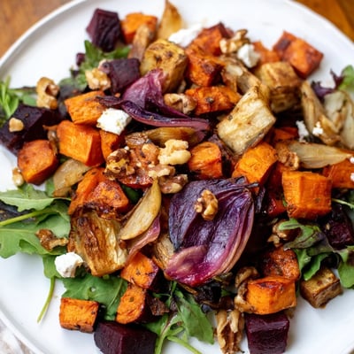 Golden caramelized root vegetables with red onion and beets are arranged on arugula with feta and toasted walnuts.