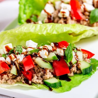 A close-up shows Italian Lettuce Wraps topped with creamy mozzarella, fresh basil, and a drizzle of balsamic glaze.