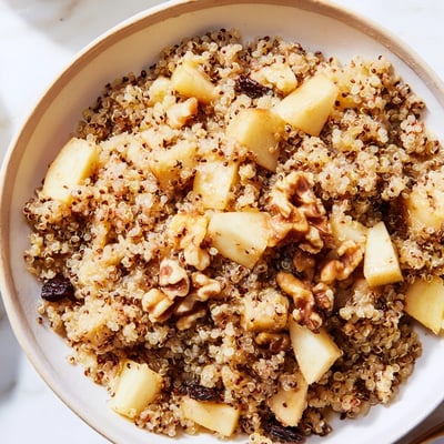 Healthy Quinoa Apple Breakfast served in a white bowl, drizzled with honey and sprinkled with cinnamon.