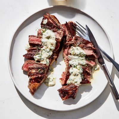 Sliced Juicy Steak With Creamy Garlic Sauce on a rustic plate beside a crisp green salad.