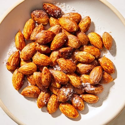 Warm roasted almonds glistening with olive oil on a parchment-lined baking sheet