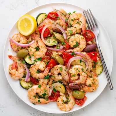Golden seared shrimp in a vibrant Mediterranean Shrimp Skillet served with lemon wedges.